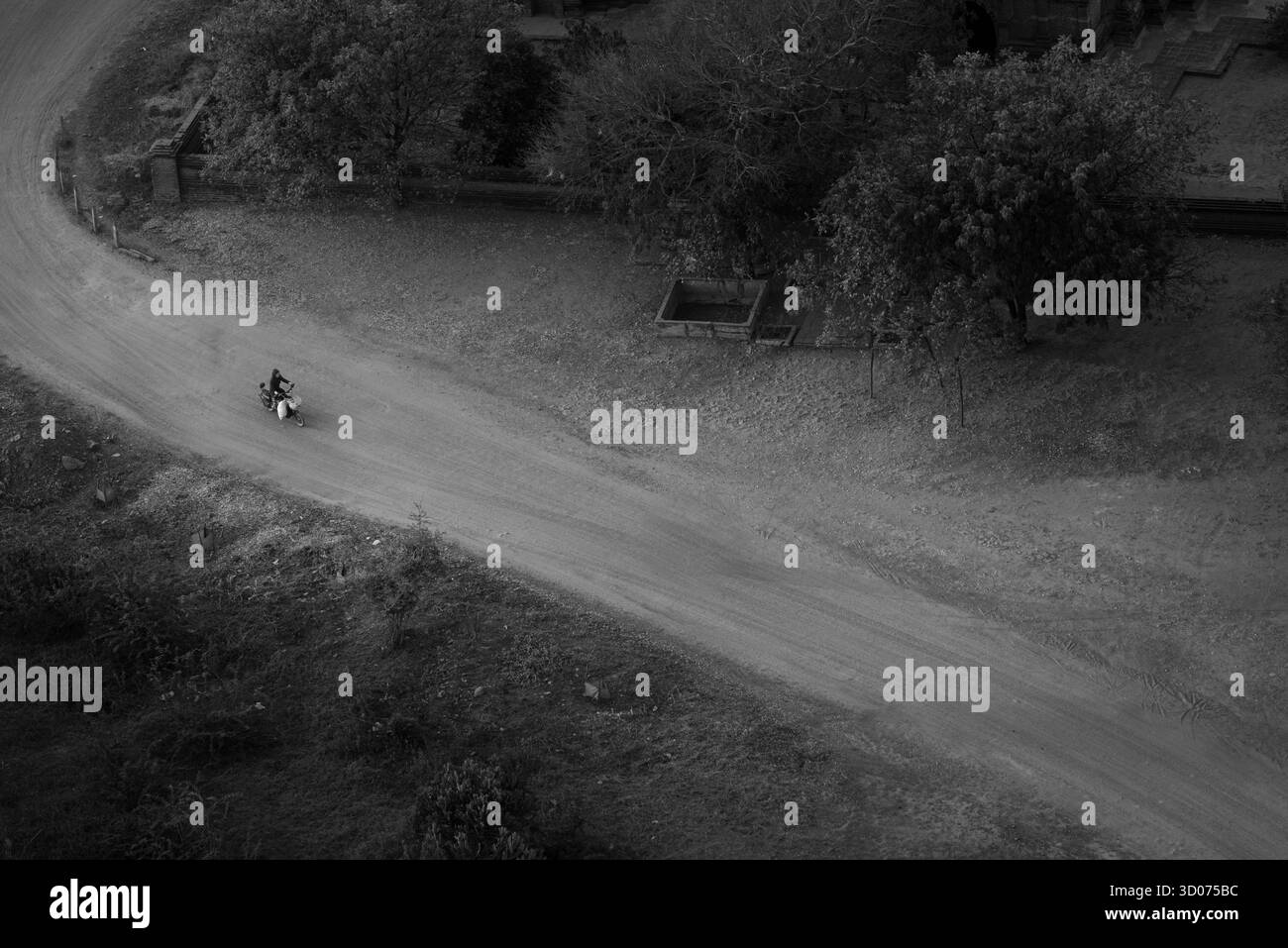 Motocycliste solitaire sur Dusty rural Road — scène aérienne minimale en noir et blanc de solitude, de liberté et de voyage à la campagne Banque D'Images