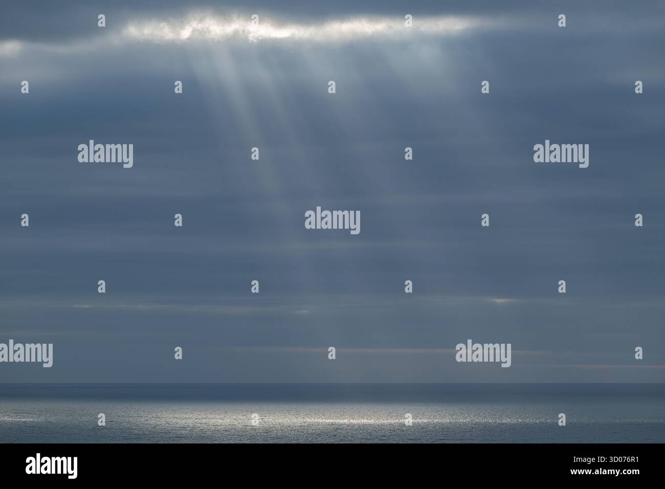 Rayons de soleil célestes sur la mer calme - des faisceaux de lumière du ciel spectaculaires brillent à travers les nuages sur l'océan Horizon en toute sérénité Banque D'Images