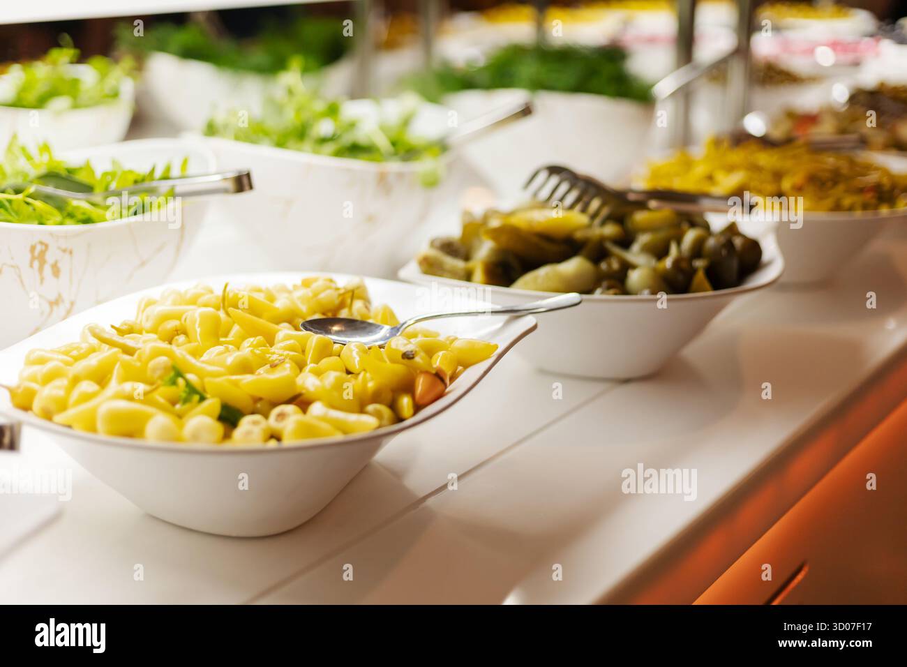 Un buffet dynamique présente des bols de pâtes, de laitue et de cornichons. Les couleurs vives et les textures invitent les invités à créer leur propre délicieux mea Banque D'Images