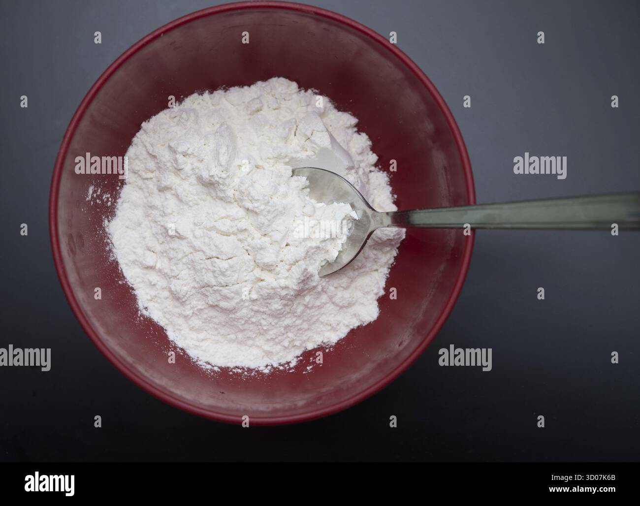 Farine blanche dans un bol sur fond noir Banque D'Images