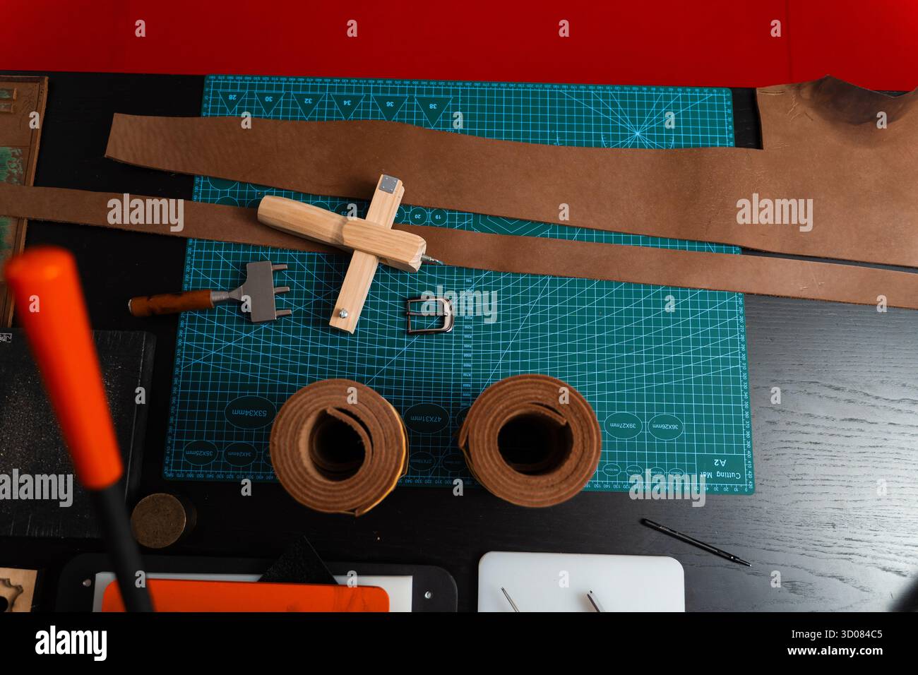 Installation de travail du cuir avec des outils, une boucle et des bandes de cuir disposées soigneusement sur un tapis, prêt pour la fabrication de ceinture. Outils de maroquinerie et fabrication de courroies p Banque D'Images