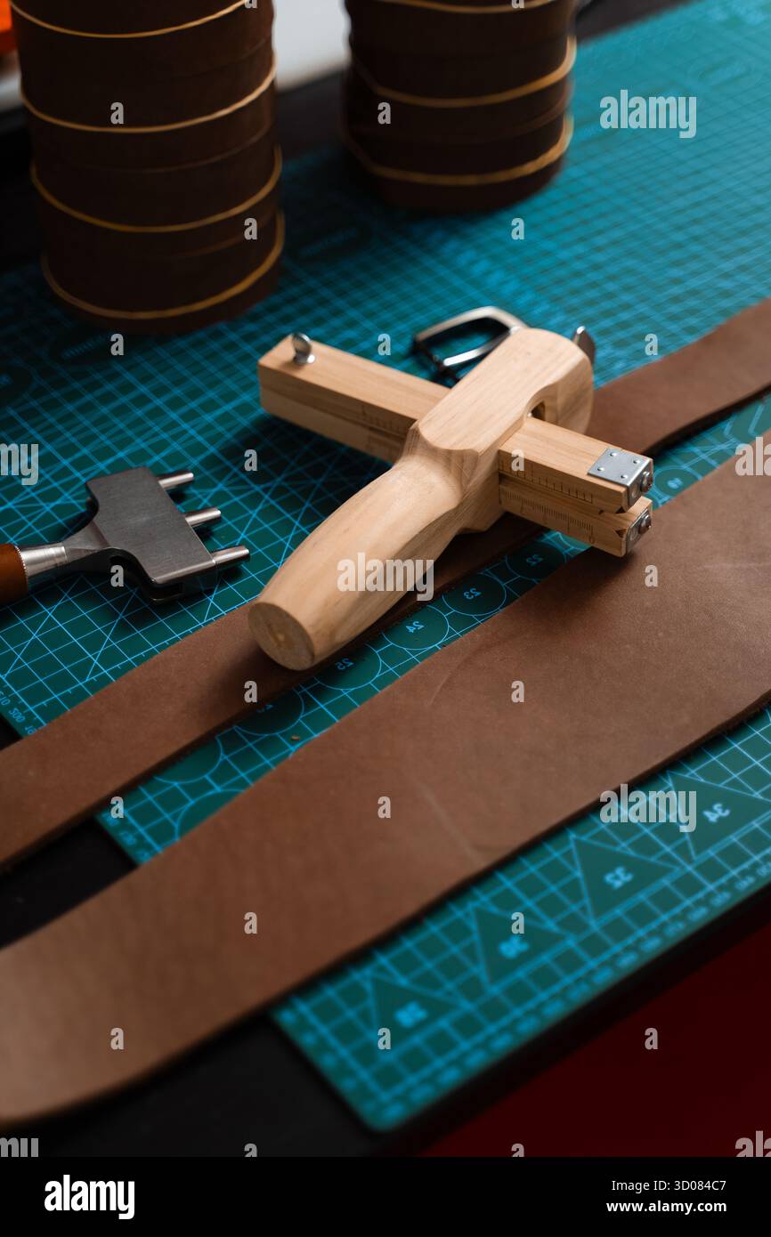 Installation de travail du cuir avec des outils, une boucle et des bandes de cuir disposées soigneusement sur un tapis, prêt pour la fabrication de ceinture. Outils de maroquinerie et fabrication de courroies p Banque D'Images
