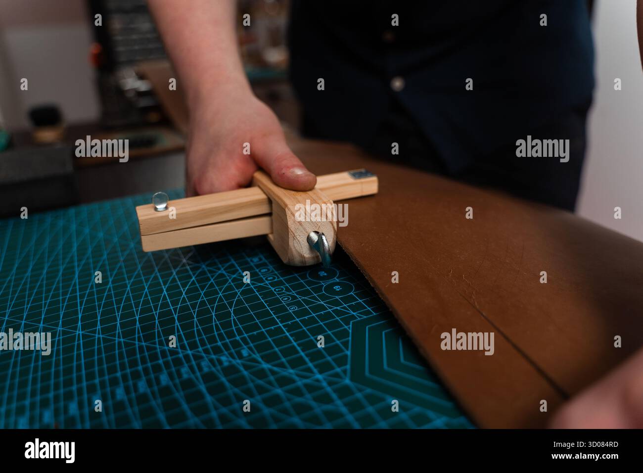 Artisan préparant le bracelet en cuir à l'aide d'un couteau en bois sur le tapis. Préparation de ceinture en cuir à la main avec coupe-sangle en bois sur le tapis de coupe. Artisan est Cu Banque D'Images