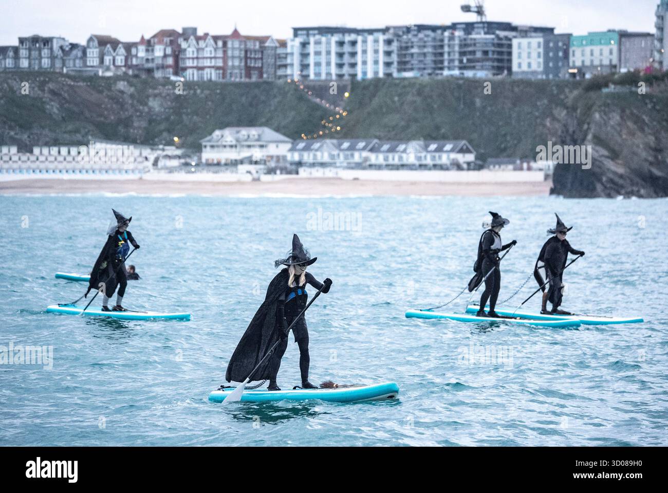 DATE DE CORRECTION RETRANSMISE les paddleboarders du Newquay Activity Centre entrent dans l'esprit d'Halloween lors d'une pagaie tôt le matin à l'aube à travers Newquay Bay à Cornwall, où les amateurs de sports nautiques préparent des tenues pour une semaine de célébration des activités dans la ville balnéaire pendant Spooky Newquay pendant les vacances d'Halloween, à partir du samedi 25 octobre. Date de la photo : mercredi 22 octobre 2025. Banque D'Images