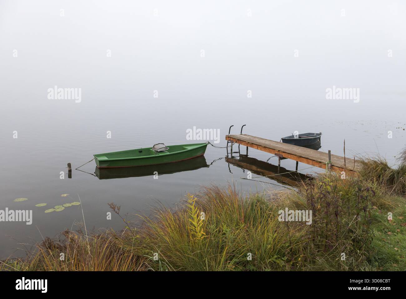 Deux bateaux et une jetée dans un environnement automnal et brumeux, Hopfensee, Ostallgaeu, Bavière, Allemagne Banque D'Images Deux bateaux et une jetée dans un environnement automnal et brumeux, Hopfensee, Ostallgaeu, Bavière, Allemagne Banque D'Images