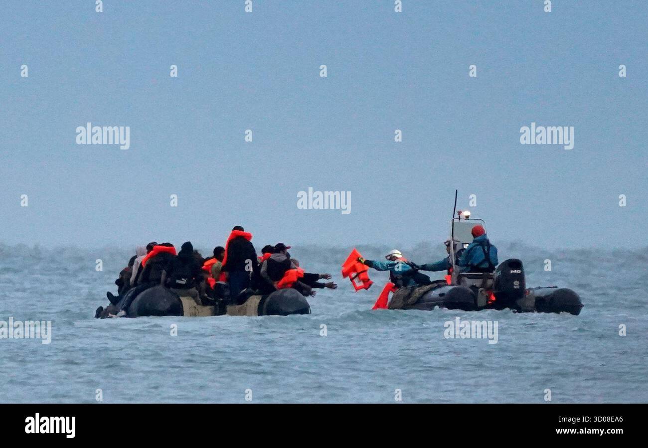 Les personnes considérées comme des migrants reçoivent des gilets de sauvetage par les autorités françaises alors qu’elles quittent la plage à bord d’un petit bateau à Gravelines, en France. Date de la photo : mercredi 22 octobre 2025. Banque D'Images