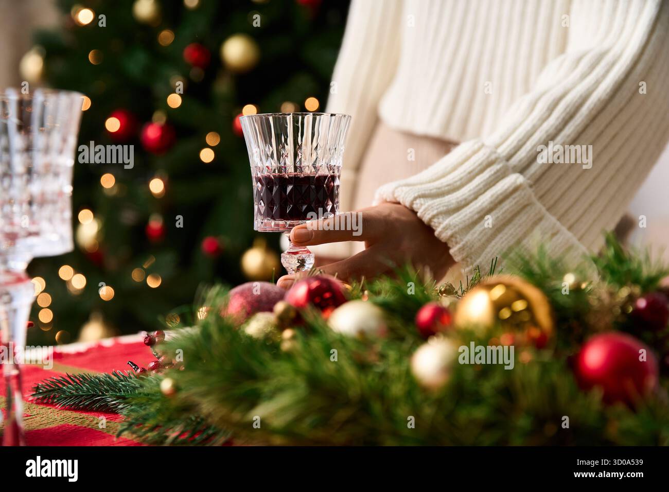 Une main tient une boisson festive près de belles décorations de Noël et un arbre décoré. Banque D'Images