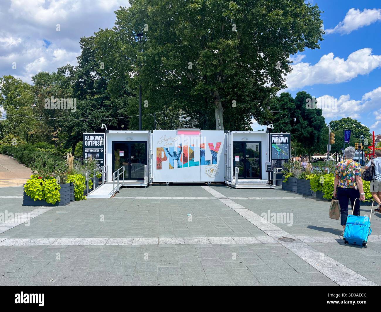 Une femme marche devant un bâtiment qui dit "pop up" dessus. Le bâtiment est en face d'un arbre et a un panneau qui dit "Philly" dessus Banque D'Images Une femme marche devant un bâtiment qui dit "pop up" dessus. Le bâtiment est en face d'un arbre et a un panneau qui dit "Philly" dessus Banque D'Images