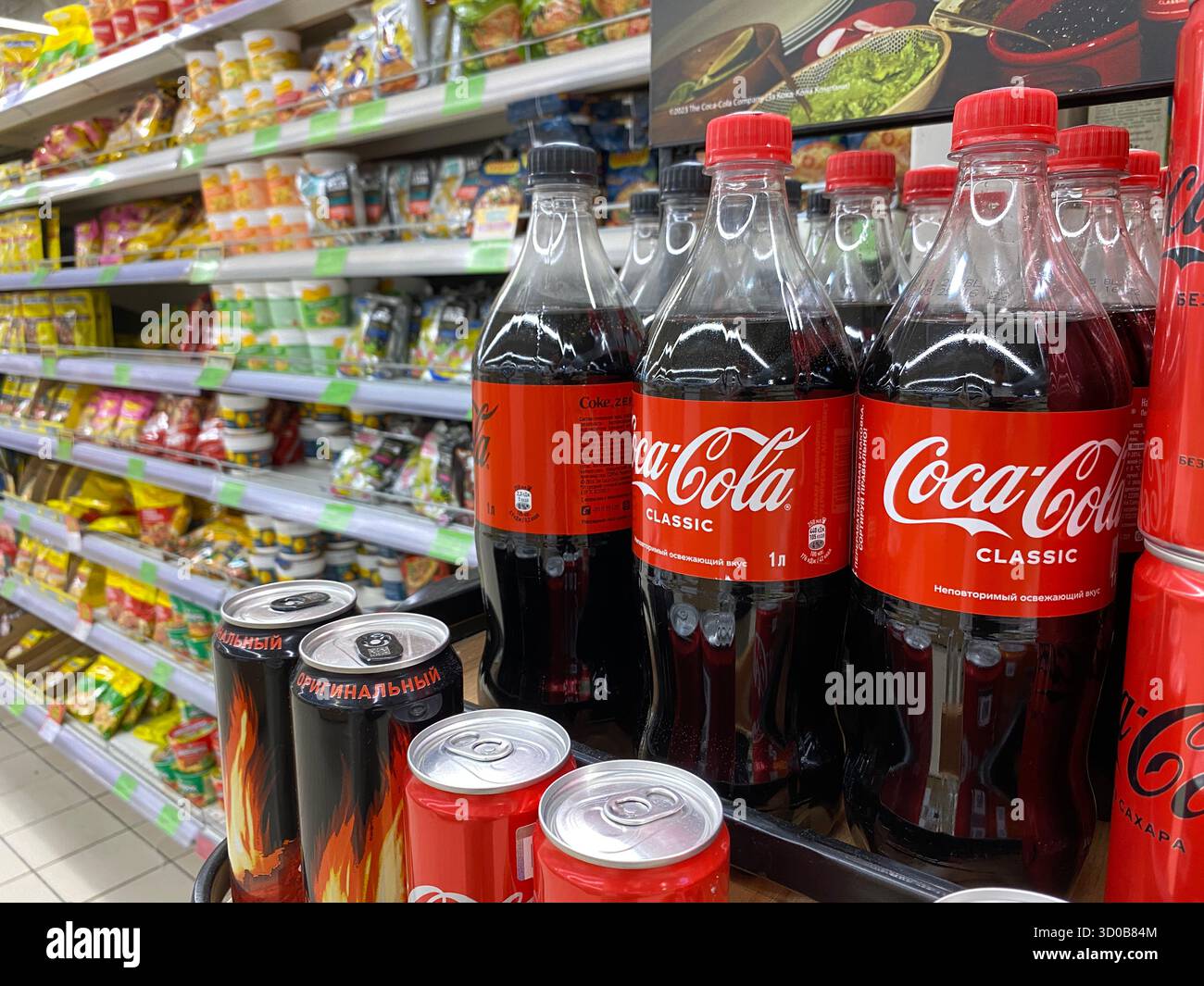 15 juillet 2025, Vitebsk, Biélorussie. Les bouteilles de Coca-Cola sont placées bien en vue à proximité de diverses collations dans une allée de supermarché bien approvisionnée. Banque D'Images