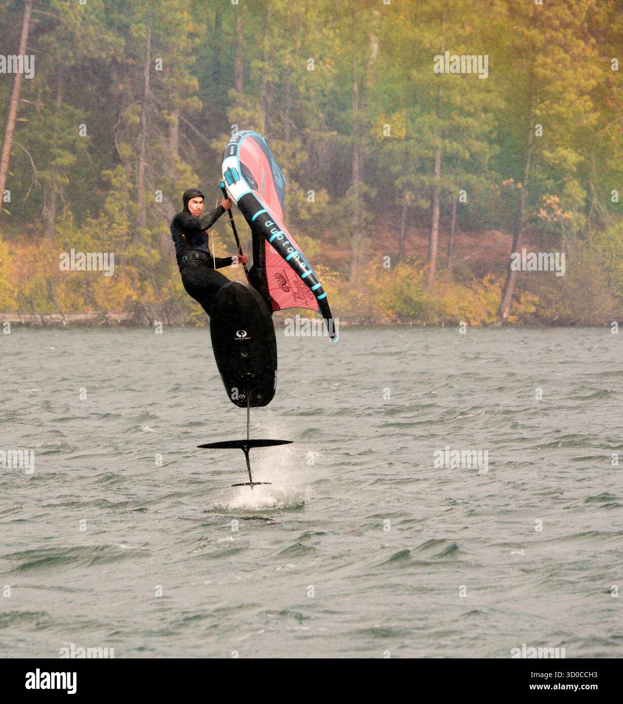 Voilage (également connu sous le nom de Wing Surf ou Winging) avec un vent fort soufflant sur le lac Suttle dans les montagnes Cascade du centre de l'Oregon en octobre. Banque D'Images