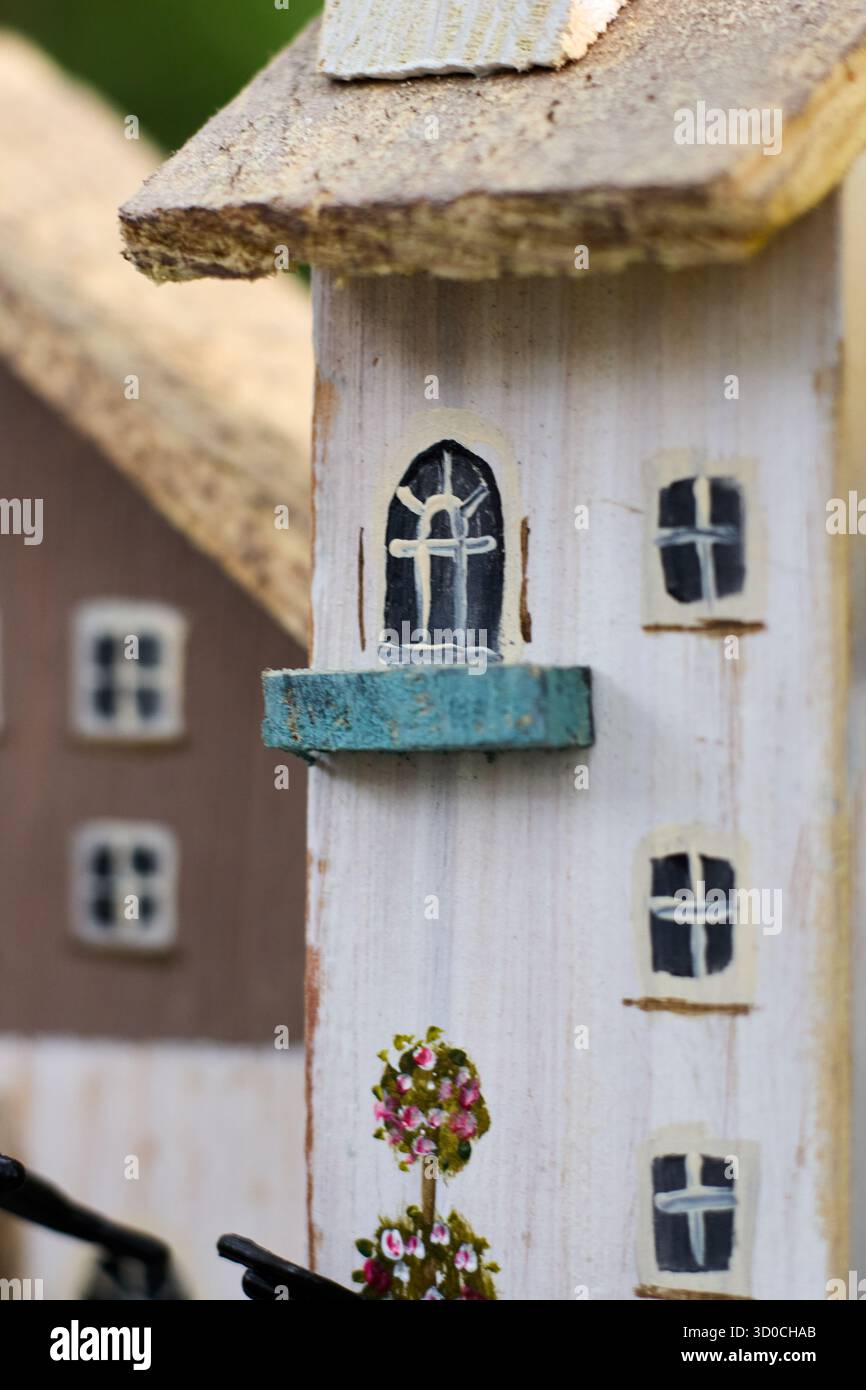 Gros plan d'une charmante maison miniature fantaisiste en bois avec des détails peints, dégageant un sentiment de singularité et d'artisanat. Banque D'Images