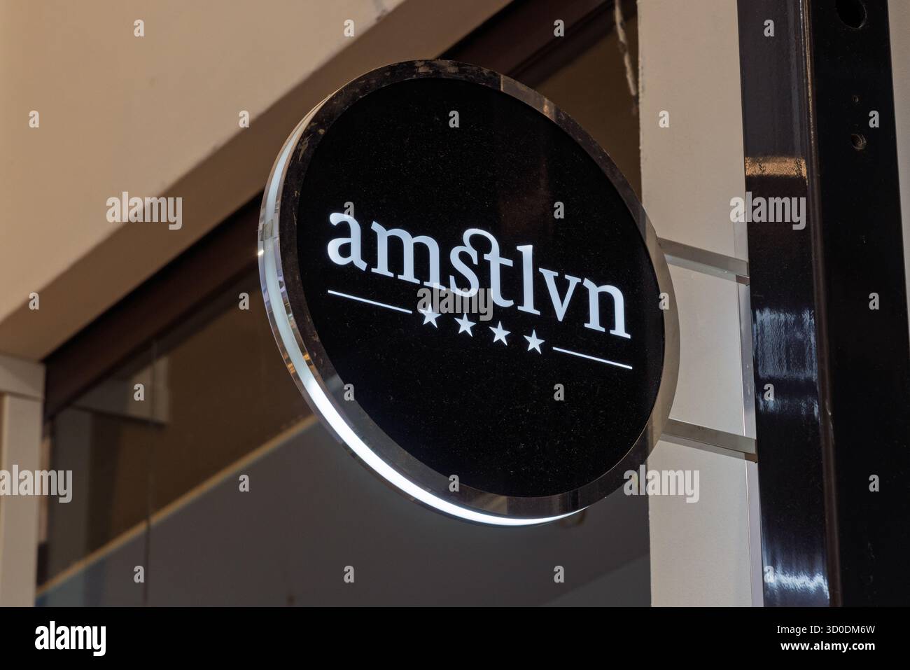 Un panneau circulaire lumineux pour le centre commercial amstelveen (stylisé amstlvn) avec un logo blanc et quatre étoiles sur fond noir. A Banque D'Images