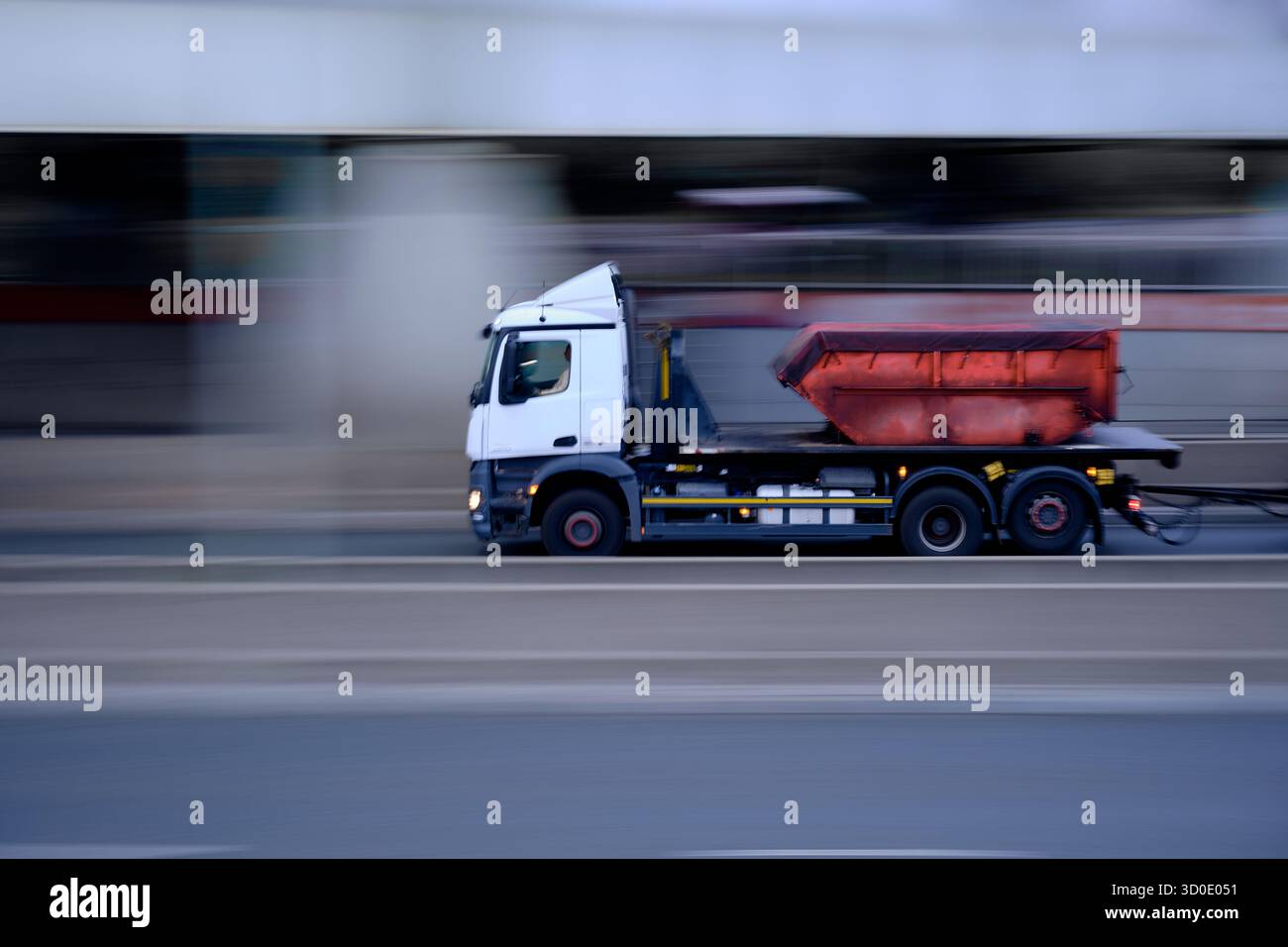 Camion avec conteneur rouge en mouvement sur la rue de la ville, fond flou montrant la vitesse de transport et le concept logistique. Banque D'Images