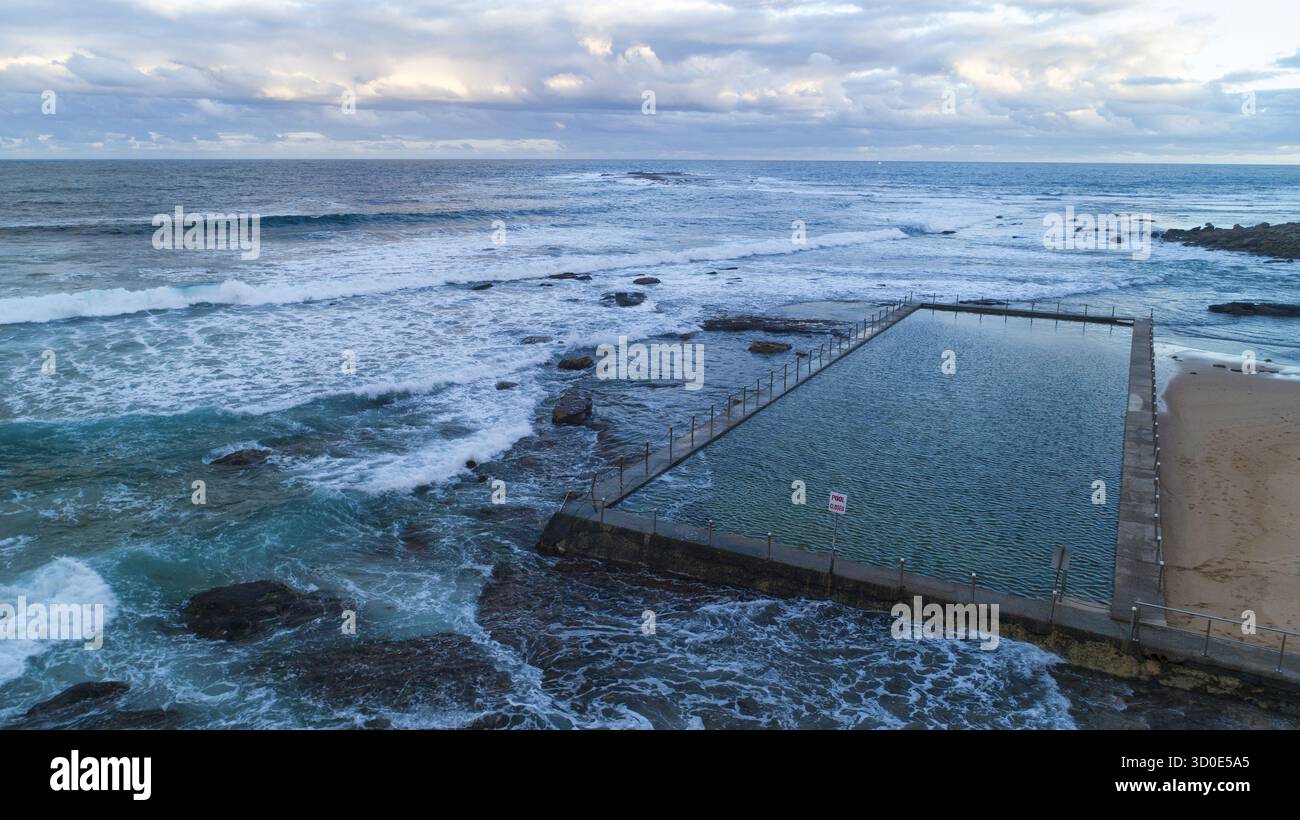Vue aérienne de la piscine océanique embrassée par des rivages rocheux et des vagues écrasantes sous un ciel nuageux à North Narrabeen, Sydney, Nouvelle-Galles du Sud, Australie. Banque D'Images