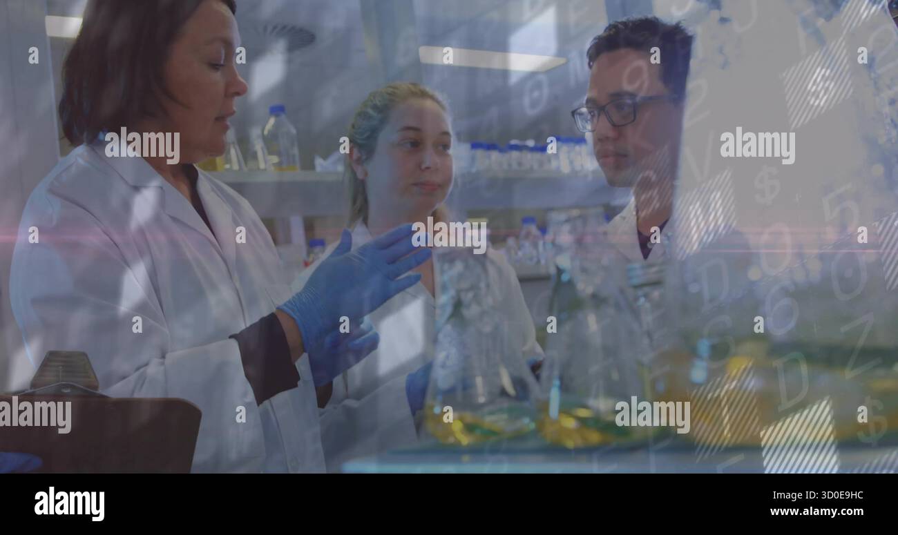 Scientifique gestuelle en blouse de laboratoire guidant ses collègues en laboratoire, avec des flacons de liquides jaunes et verts Banque D'Images