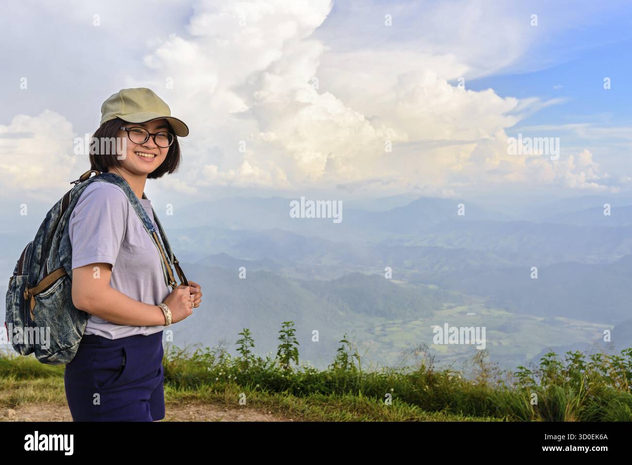 Adolescent fille randonneur porter une casquette et des lunettes avec sac à dos est debout et souriant joyeusement sur la haute montagne au point pittoresque de Phu Chi Fa Forest Park en CH Banque D'Images