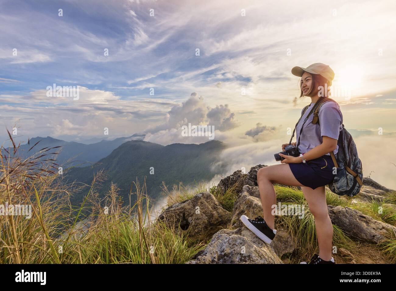 Randonneur asiatique jeune femme heureuse avec un sac à dos et des casquettes d'appareil photo regardant beau paysage nature de montagne et ciel coloré au coucher du soleil sur le point de vue pH Banque D'Images
