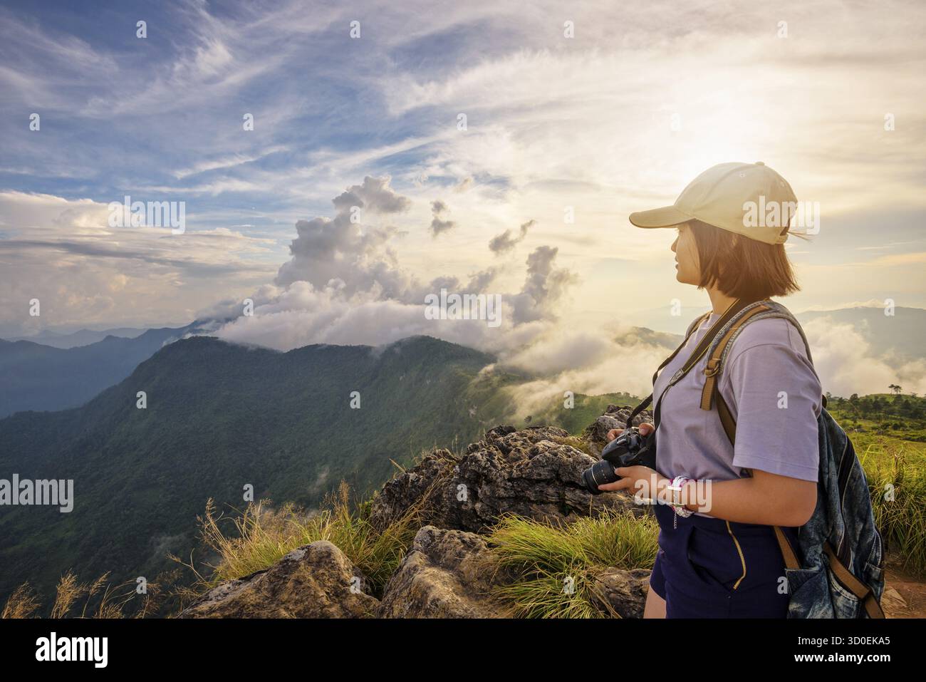 Randonneur asiatique jeune femme heureuse avec un sac à dos et des casquettes d'appareil photo regardant beau paysage nature de montagne et ciel coloré au coucher du soleil sur le point de vue pH Banque D'Images