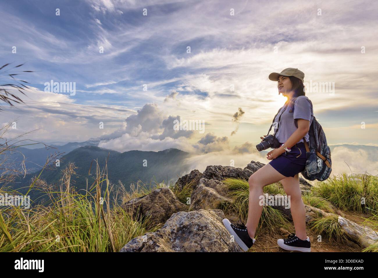 Randonneur asiatique jeune femme heureuse avec un sac à dos et des casquettes d'appareil photo regardant beau paysage nature de montagne et ciel coloré au coucher du soleil sur le point de vue pH Banque D'Images
