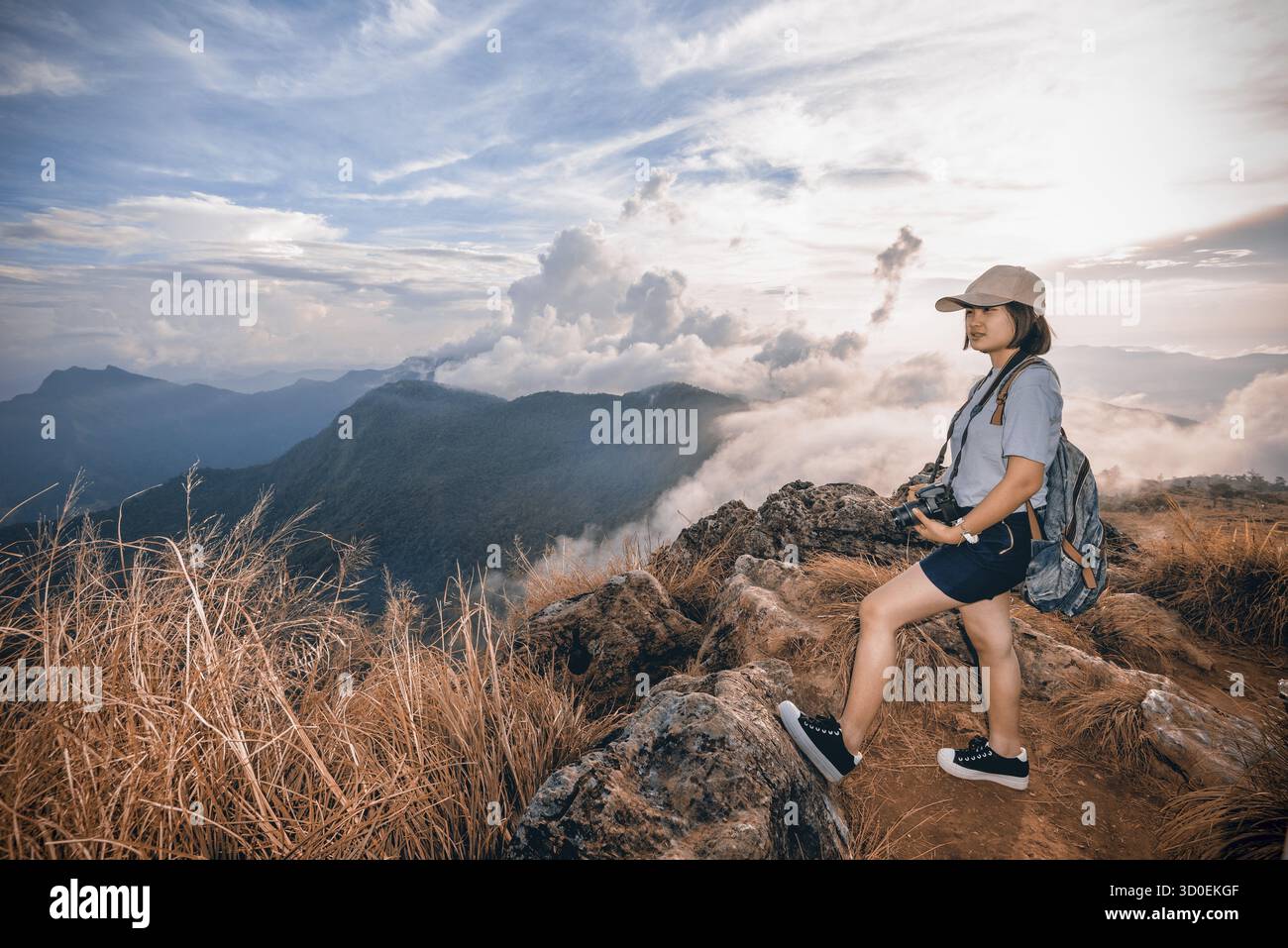 Randonneur de style vintage jeune femme heureuse avec appareil photo et sac à dos regardant belle nature de paysage de montagne dans Phu Chi Fa Forest Park, Chiang Rai, T. Banque D'Images