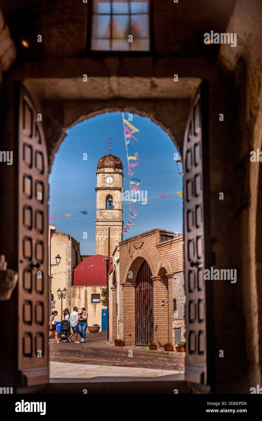 Vue encadrée de l'église de San Pietro Apostolo et son clocher à Assemini, Sardaigne, Italie, pendant une journée ensoleillée avec drapeaux festifs Banque D'Images