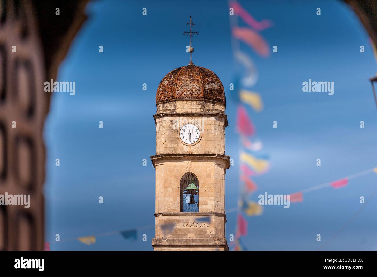 Vue encadrée de l'église de San Pietro Apostolo et son clocher à Assemini, Sardaigne, Italie, pendant une journée ensoleillée avec drapeaux festifs Banque D'Images