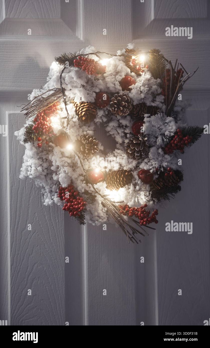 Couronne de Noël et de la lumière sur une porte avant blanc Banque D'Images