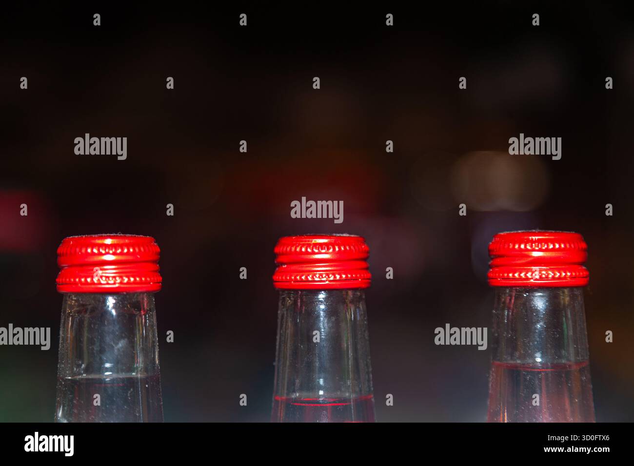 Dessus des bouteilles en verre avec des bouchons en fer fermés sur fond flou dans une pièce sombre avec des lumières Banque D'Images