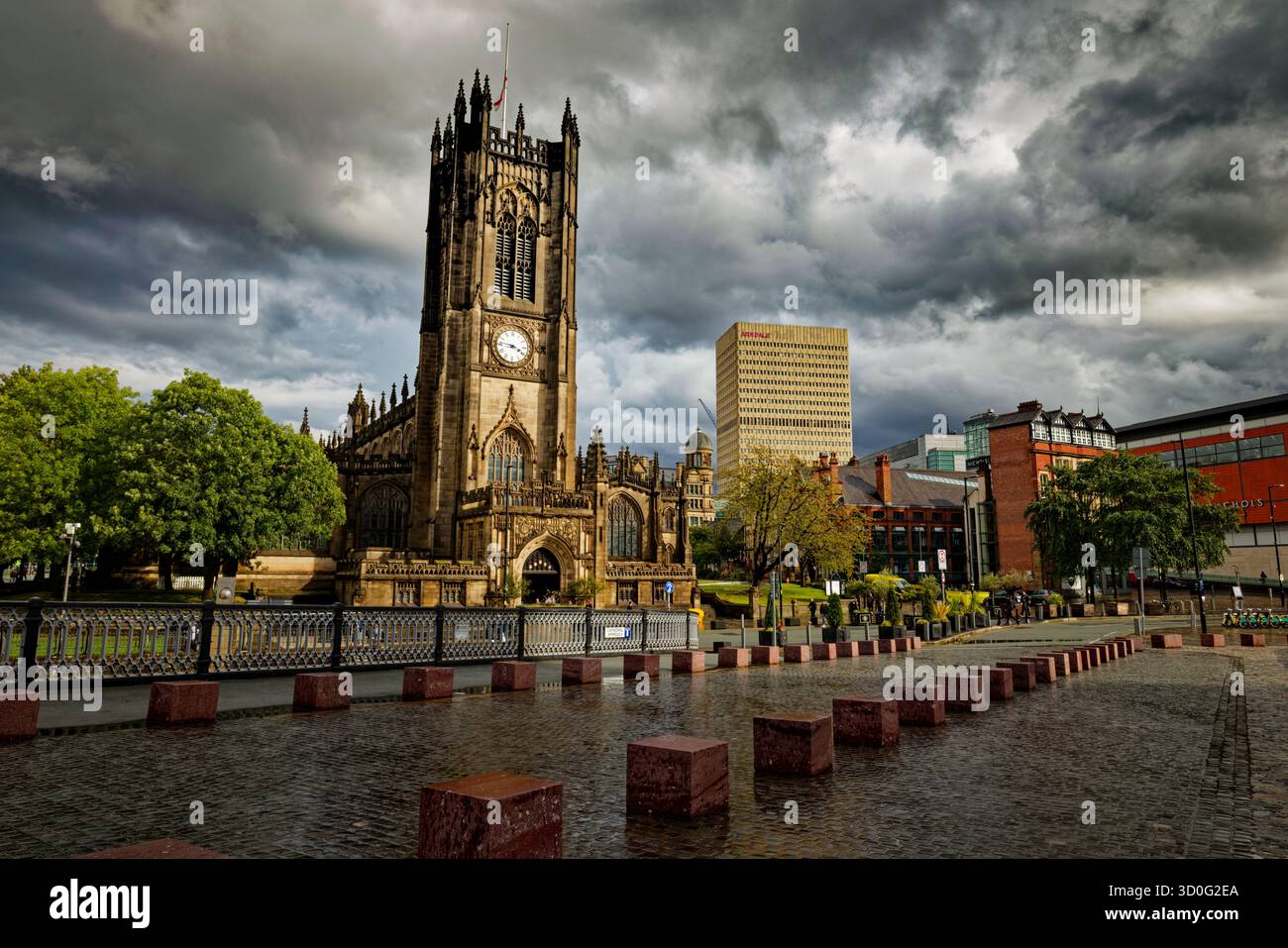 Une vue de l'autre côté d'un Wet Exchange Square jusqu'à la cathédrale de Manchester alors que les nuages de tempête se brisent, avec l'horizon du centre-ville au-delà, Manchester, Angleterre. Banque D'Images