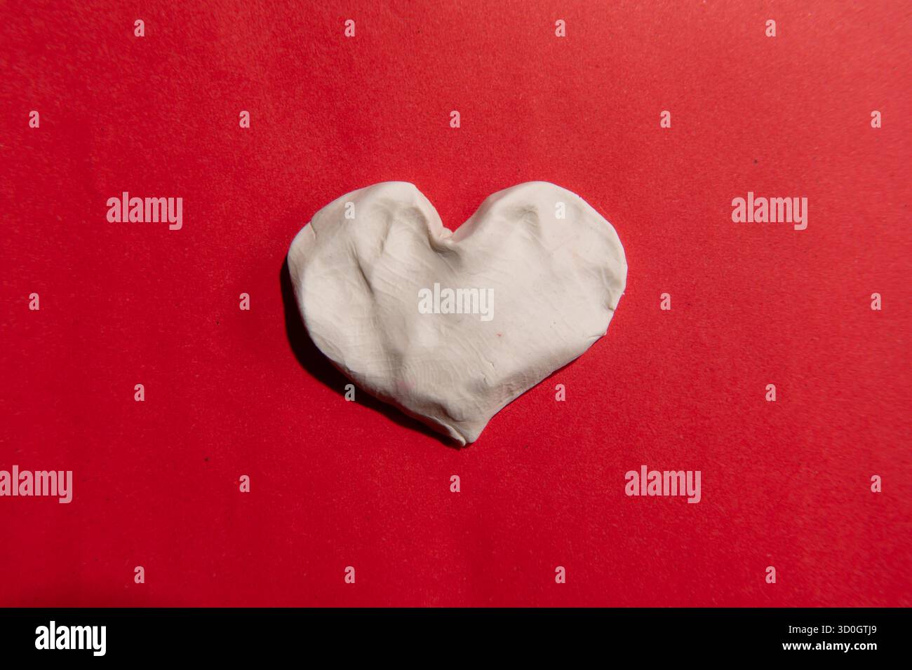 Coeur d'argile blanche sur papier rouge Banque D'Images