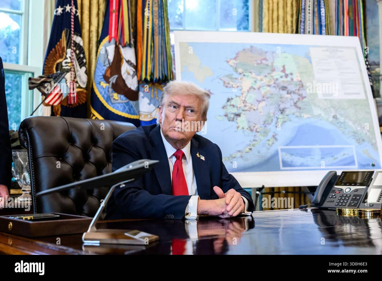 Le président Donald Trump est assis au Resolute Desk avec la carte de l’Alaska affichée derrière lui après avoir signé le décret approuvant le projet de la route Ambler. 6 octobre 2025. Washington, D.C. image reproduite avec l'aimable autorisation de la Maison Blanche. Banque D'Images