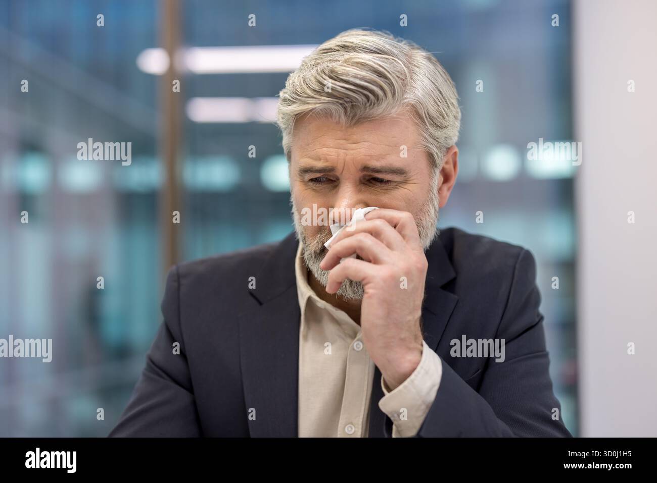 Homme d'affaires mature éprouvant la détresse émotionnelle ou la tristesse, essuyant les larmes avec un mouchoir, transmettant des concepts de deuil, de stress, de perte, d'anxiété et de vulnérabilité dans un cadre d'entreprise Banque D'Images