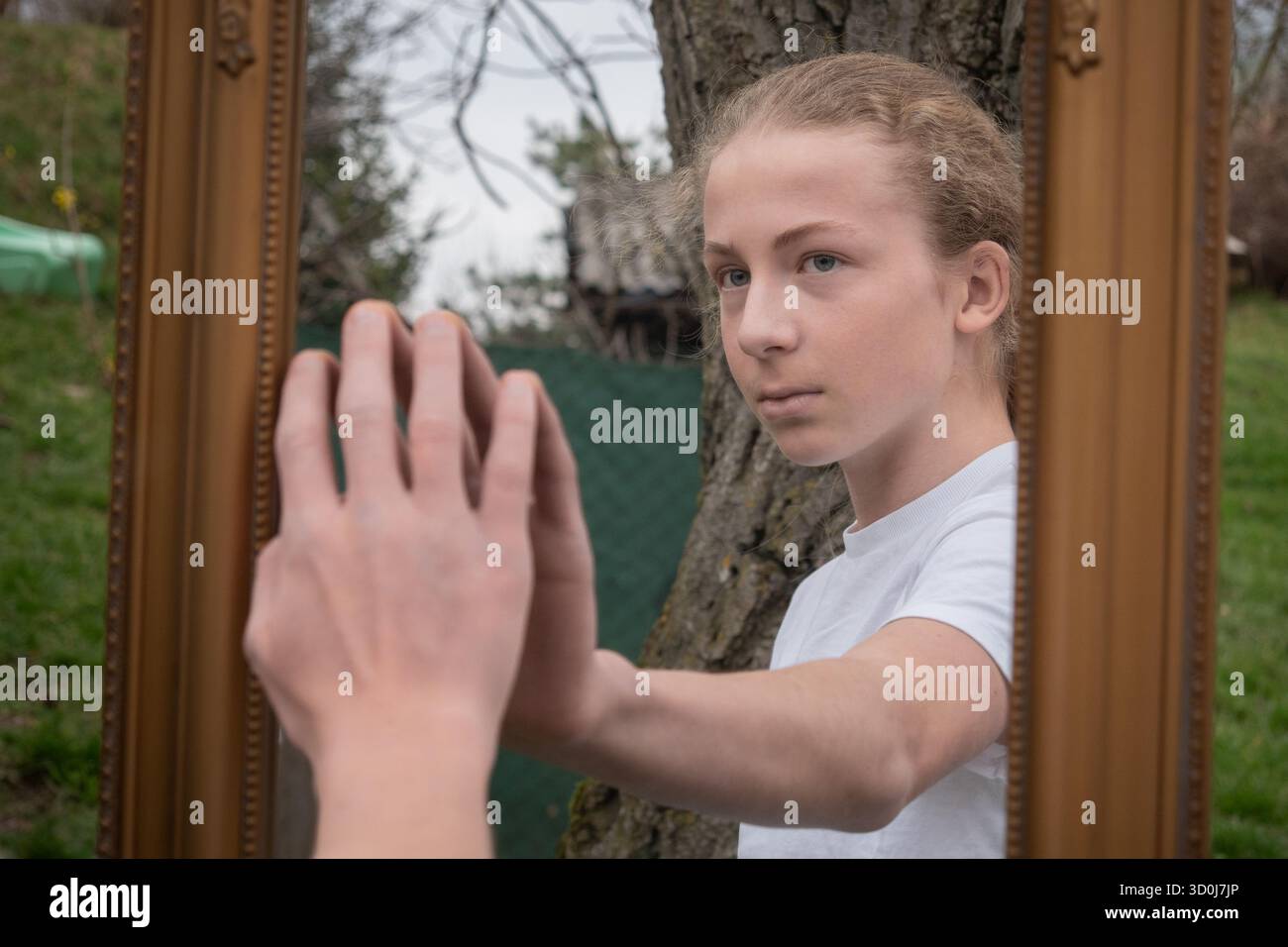 Jeune personne touchant le reflet miroir à l'extérieur, concept d'auto-réflexion et d'identité Banque D'Images