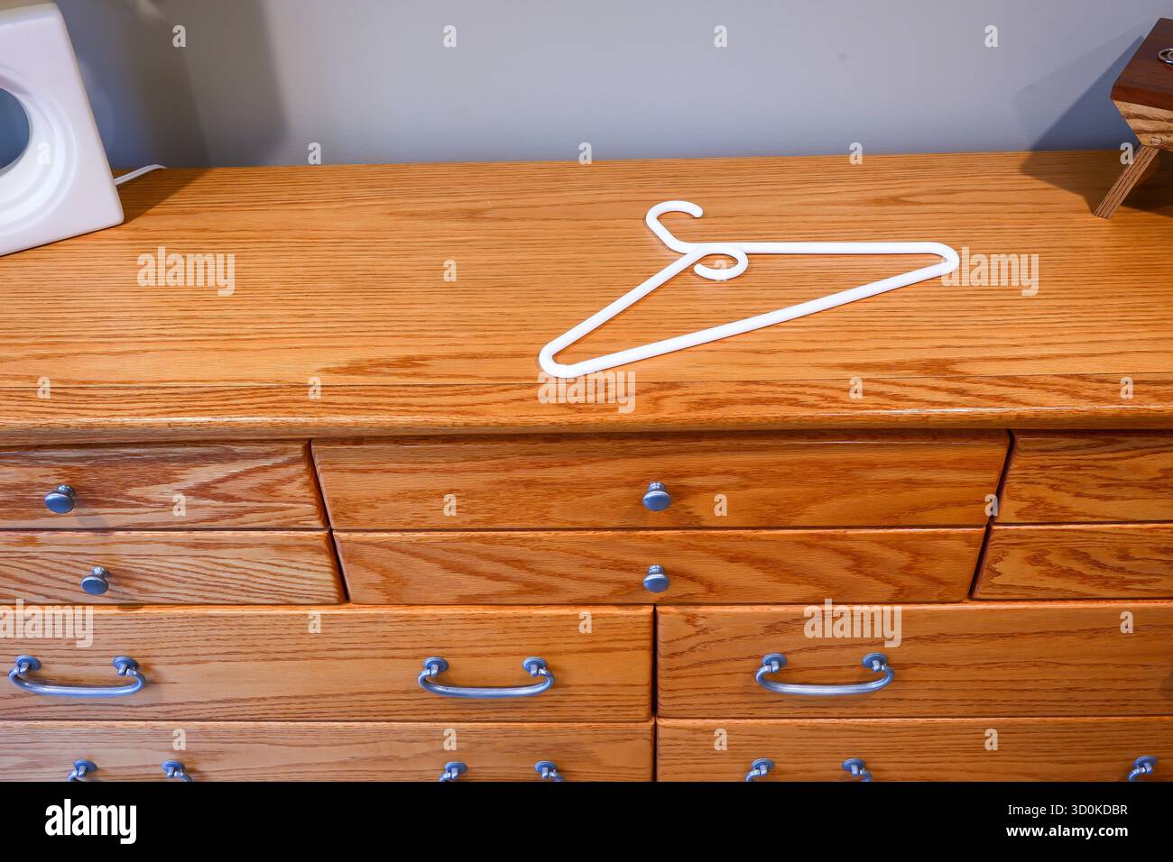 Un cintre en plastique blanc couché sur le dessus de la commode en bois ou commode. Banque D'Images