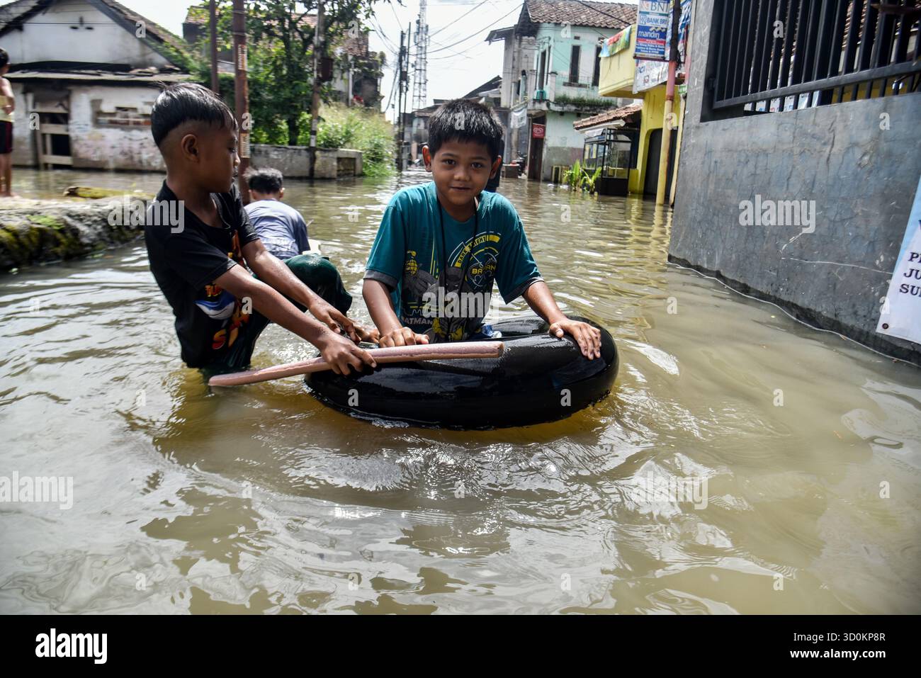 Bandung Regency, Java occidental, Indonésie. 24 octobre 2025. Les enfants jouent avec un pneu utilisé comme bateau pendant les inondations dans le village de Bojongasih, Dayeuhkolot, Bandung Regency, Java occidental. Les fortes pluies qui ont frappé Bandung à partir du jeudi 23 octobre, de l’après-midi au soir, ont laissé des centaines de maisons et de routes dans la Régence de Bandung submergées par des eaux de crue jusqu’à 40 centimètres de profondeur. (Crédit image : © Dimas Rachmatsyah/ZUMA Press Wire) USAGE ÉDITORIAL SEULEMENT ! Non destiné à UN USAGE commercial ! Banque D'Images Bandung Regency, Java occidental, Indonésie. 24 octobre 2025. Les enfants jouent avec un pneu utilisé comme bateau pendant les inondations dans le village de Bojongasih, Dayeuhkolot, Bandung Regency, Java occidental. Les fortes pluies qui ont frappé Bandung à partir du jeudi 23 octobre, de l’après-midi au soir, ont laissé des centaines de maisons et de routes dans la Régence de Bandung submergées par des eaux de crue jusqu’à 40 centimètres de profondeur. (Crédit image : © Dimas Rachmatsyah/ZUMA Press Wire) USAGE ÉDITORIAL SEULEMENT ! Non destiné à UN USAGE commercial ! Banque D'Images