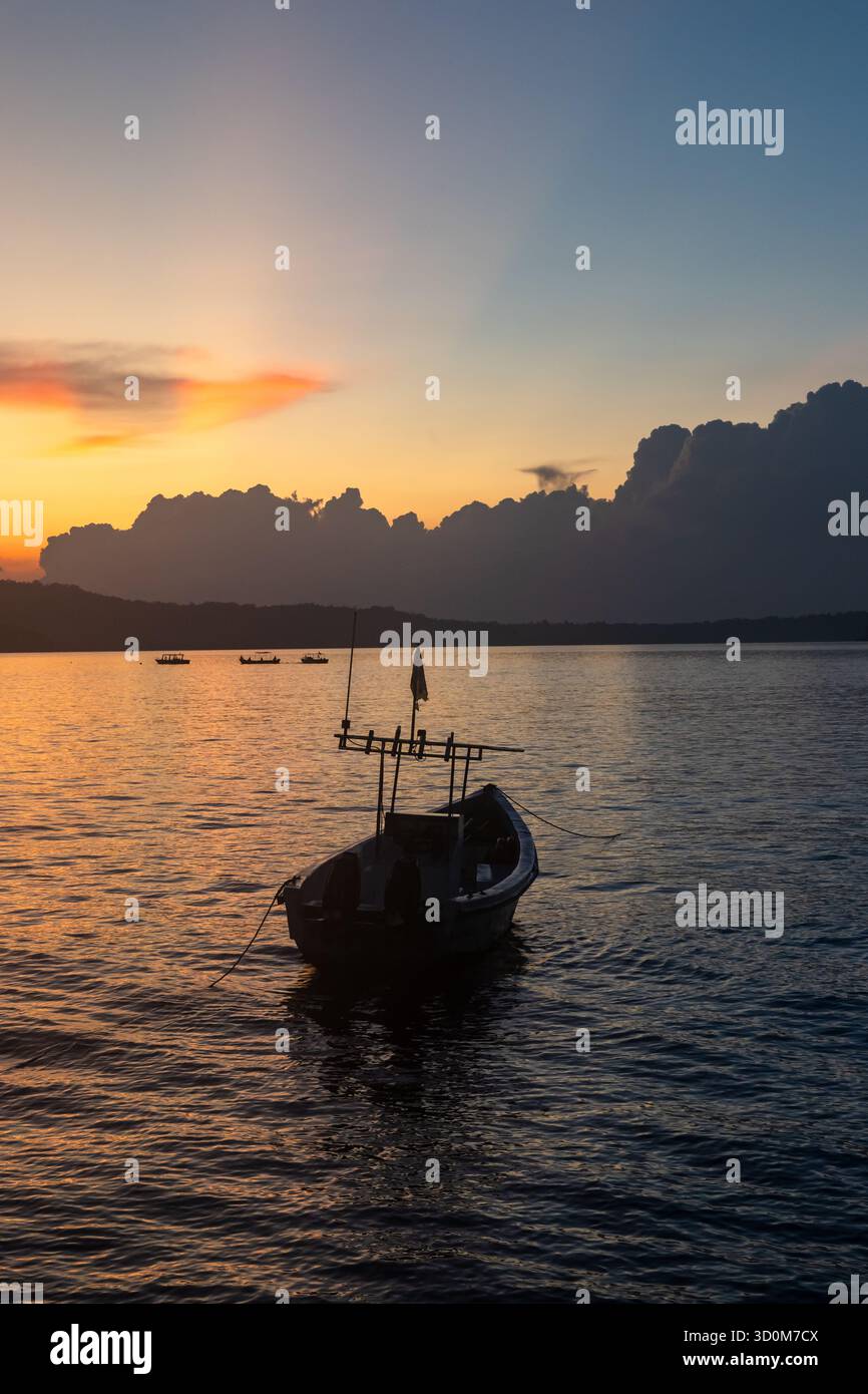 bateaux de pêche ancrés dans l'eau de fond de mer sous le ciel doré du coucher du soleil Banque D'Images