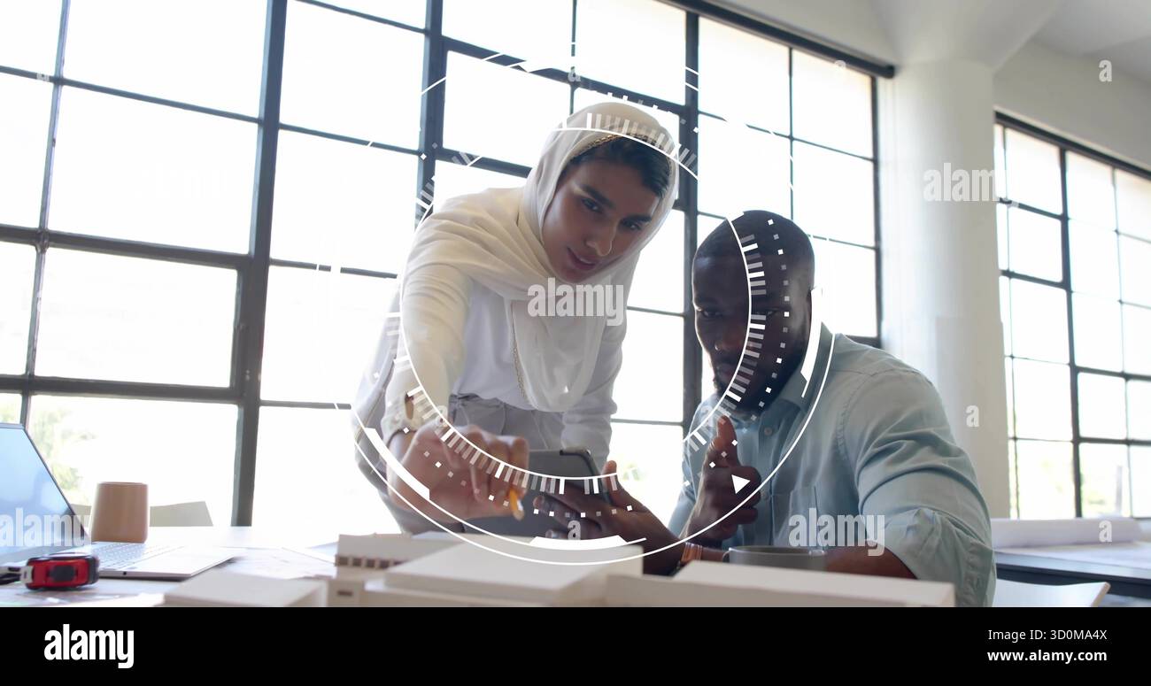 Des collègues examinent des modèles architecturaux et des plans dans un studio de design, avec des conseils sur smartphone Banque D'Images