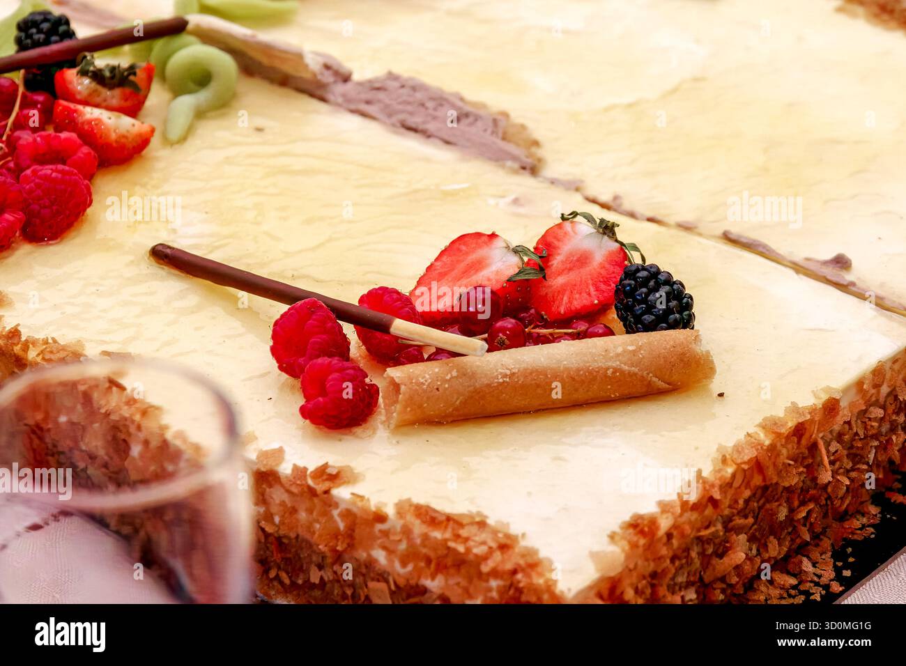 Gâteau à la crème glacée en couches décoré de fraises fraîches et de framboises, servi sur une table lors d'une occasion festive. Banque D'Images