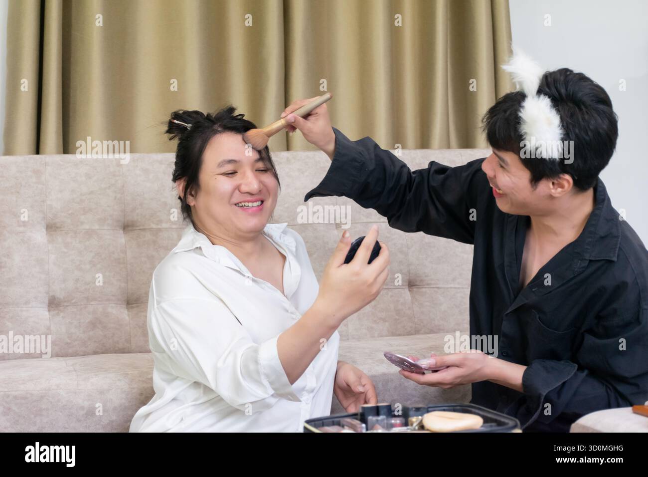 Deux amis LGBTQ thaïlandais partagent des moments de maquillage joyeux ensemble à la maison montrant l'amitié de rire et la créativité exprimant la confiance et l'inclusion n Banque D'Images