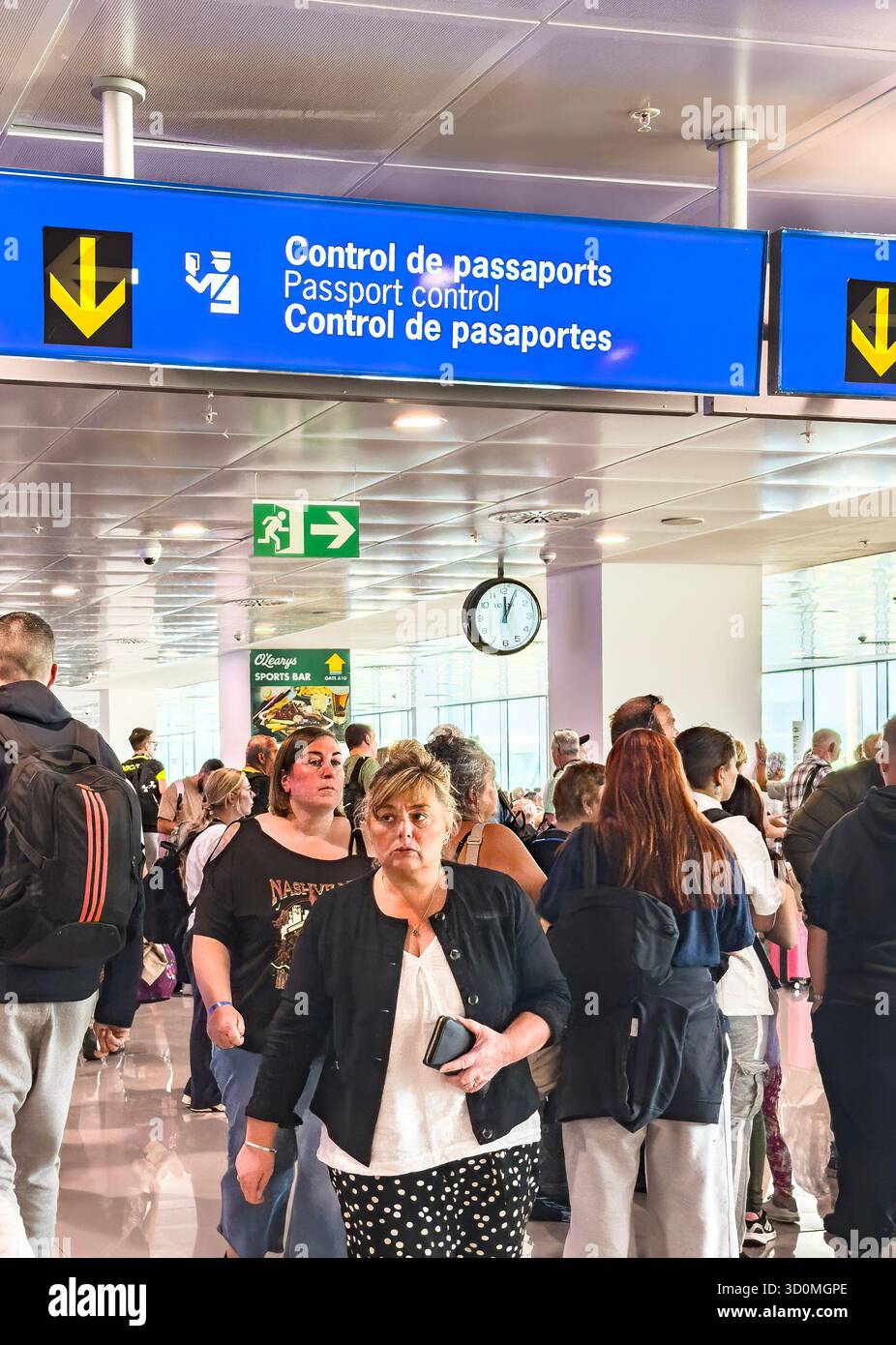 Foule de voyageurs marchant sous un panneau de contrôle des passeports au terminal de l'aéroport international de palma mallorca avec des panneaux visibles en plusieurs langues - Image de stock capturée avec un smartphone