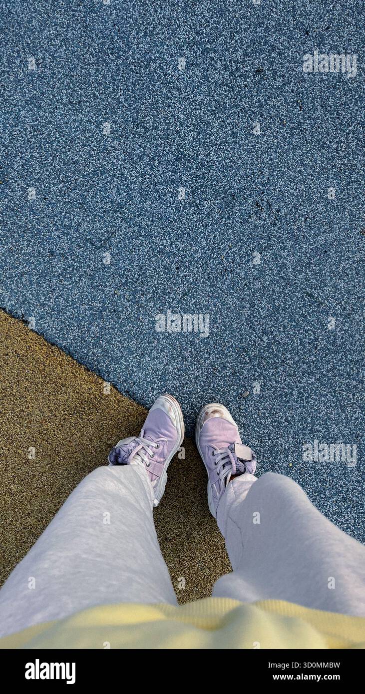 Personne debout sur un trottoir coloré, des baskets et une tenue confortable Banque D'Images