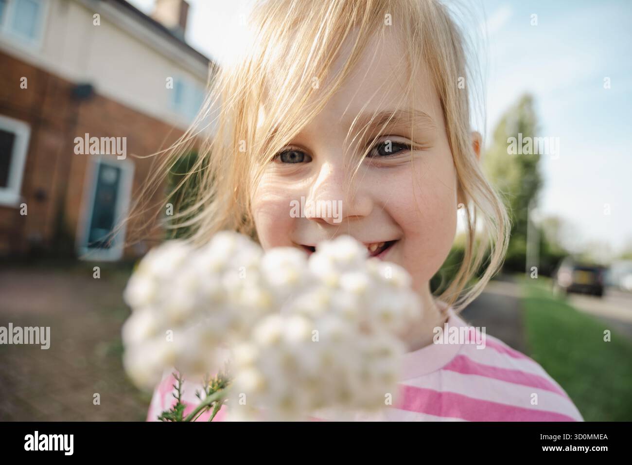 Portrait en gros plan d'une petite fille souriante tenant des fleurs blanches Banque D'Images