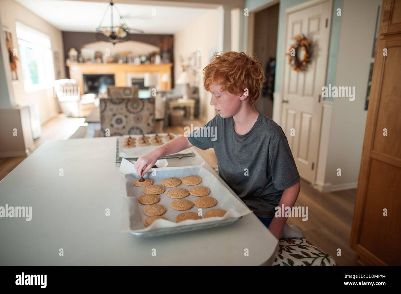 Jeune garçon qui cuit des biscuits frais à la maison dans le cadre confortable de la cuisine Banque D'Images