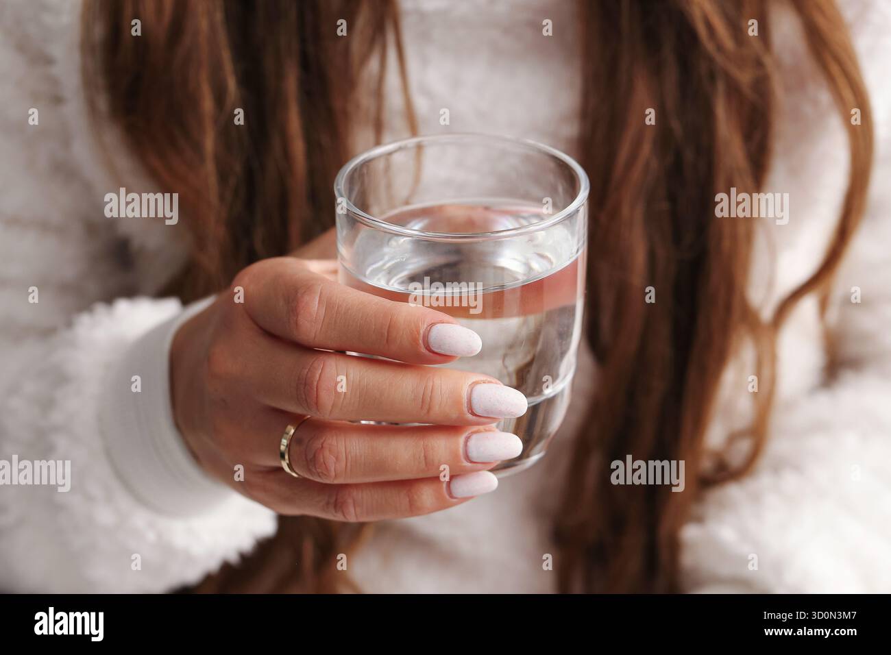 Femme tenant le verre d'eau gros plan. Eau potable claire dans la main féminine. Concept d'hydratation saine à la maison. Moment de style de vie simple avec de l'eau propre Banque D'Images