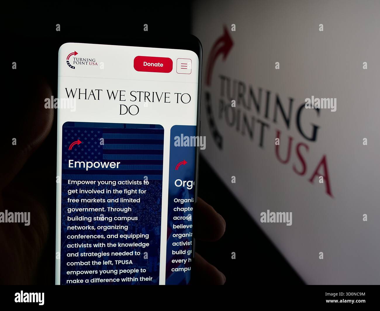 Stuttgart, Allemagne - 10-15-2025 : personne tenant un téléphone portable avec la page web de l'organisation américaine Turning point USA (TPUSA) sur l'écran devant le logo. Mise au point Banque D'Images