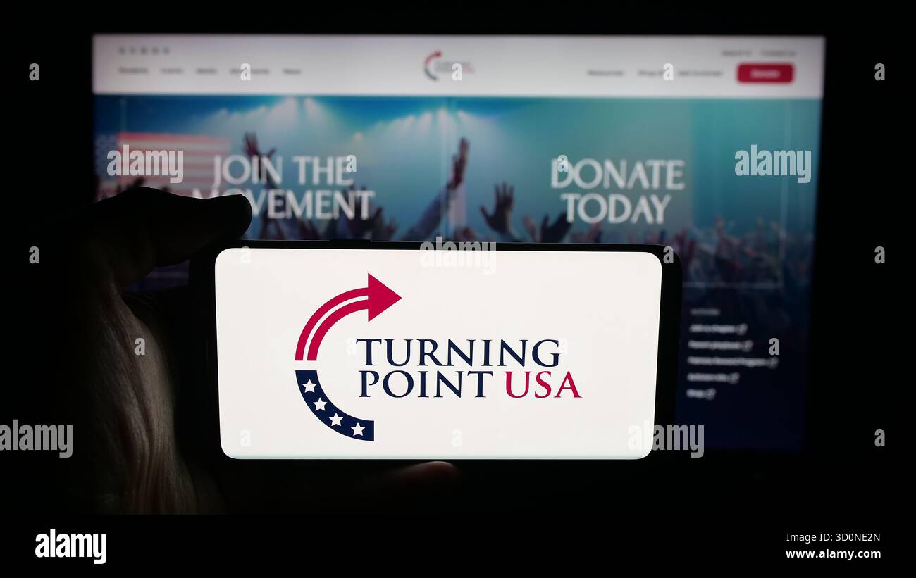 Stuttgart, Allemagne - 10-15-2025 : personne tenant un téléphone portable avec le logo de l'organisation américaine Turning point USA (TPUSA) sur l'écran devant la page web. Mise au point Banque D'Images
