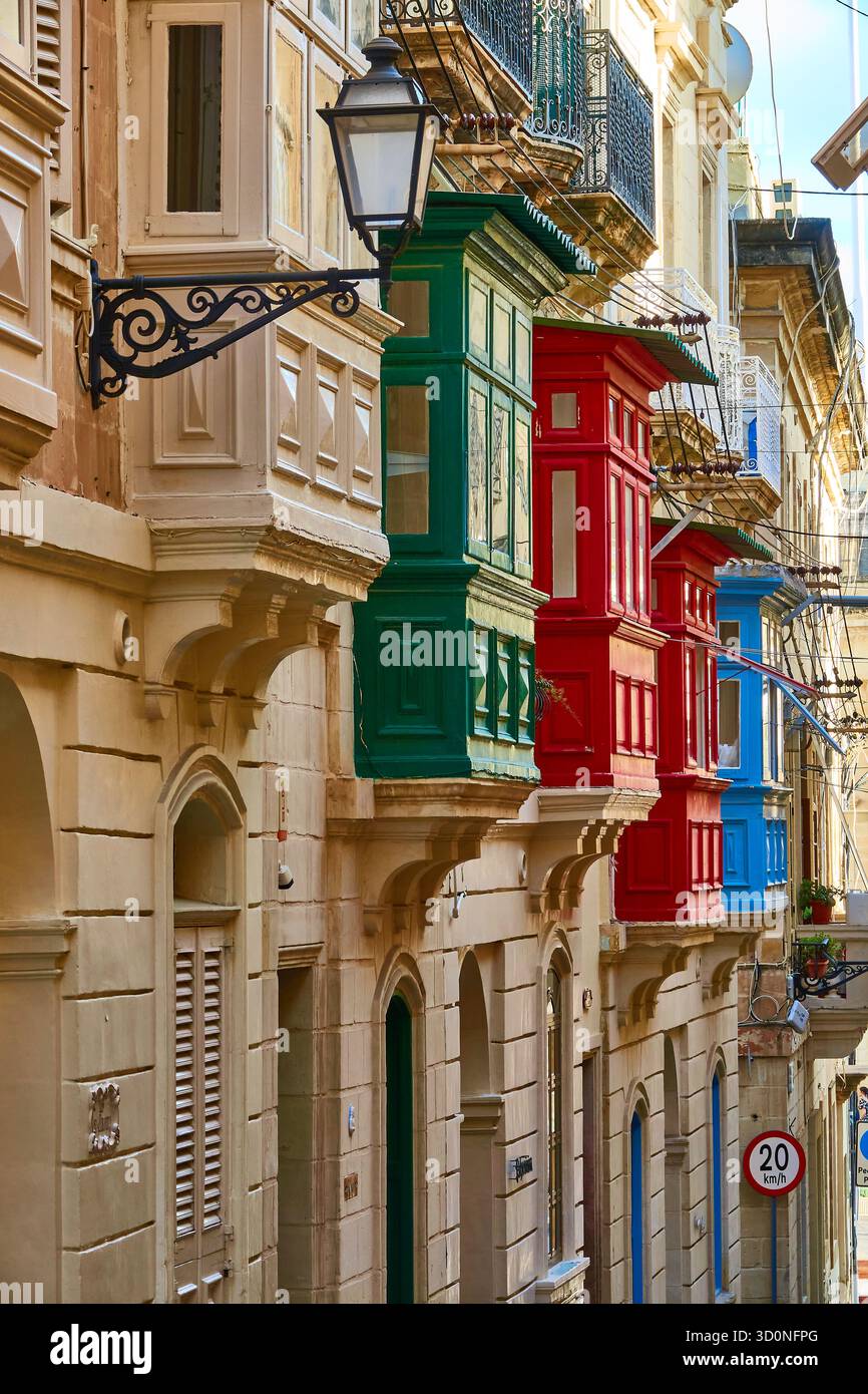 Balcons colorés donnant sur une rue maltaise étroite avec lanternes vintage et fenêtres à volets Banque D'Images