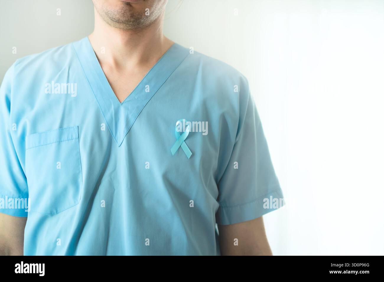 Gros plan d'un jeune professionnel de la santé en uniforme avec un ruban de satin bleu. Symbole de sensibilisation, de prévention et de diagnostic médical précoce du cancer de la prostate. Banque D'Images