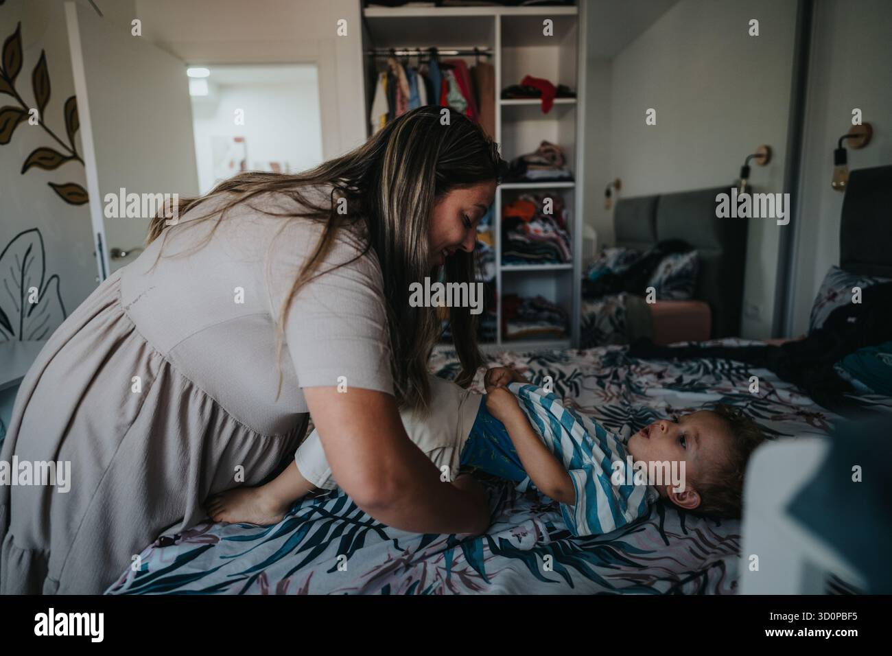 Une mère joue avec son bébé sur le lit dans une chambre confortable à la maison Banque D'Images