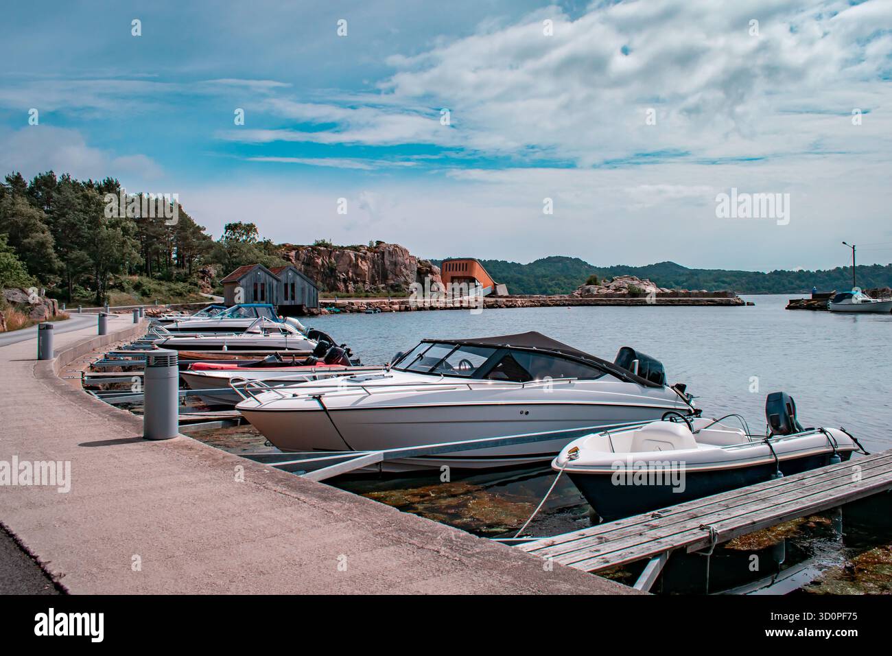 Une rangée de chalets colorés avec des bateaux amarrés à l'intérieur, reflétant sur l'eau calme. Banque D'Images